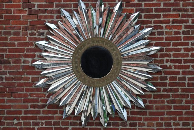 MODERN SUNBURST MIRROR: Individual pieces of mirror in brass framing, brass tipped ends, round mirror. Center surrounded by a decorated brass ring, 62"Diameter. In good condition.