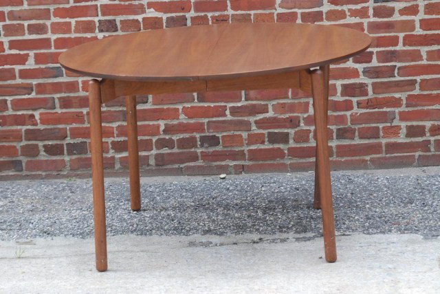 MID-CENTURY MODERN DINING ROOM TABLE: Round walnut table with 4 legs and 12" leaves, 45"D, 28-1/2"H, 69" extended. Old repairs to the legs and minor surface scratches.