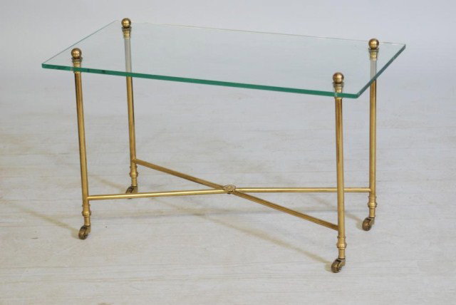 JANSEN STYLE COFFEE TABLE: Glass top on a bronze base with an "X" stretcher and wheels, 19"h 30"w x 16"d. In good condition.