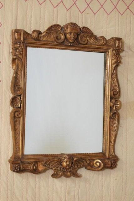 ANTIQUE ITALIAN GILT RENAISSANCE MIRROR: Winged Cherub mask cartouche at the top and bottom flanked by scroll, shell and wise man mask side rails, 43 1/2"h x 34"w. Minor losses with replaced mirror.