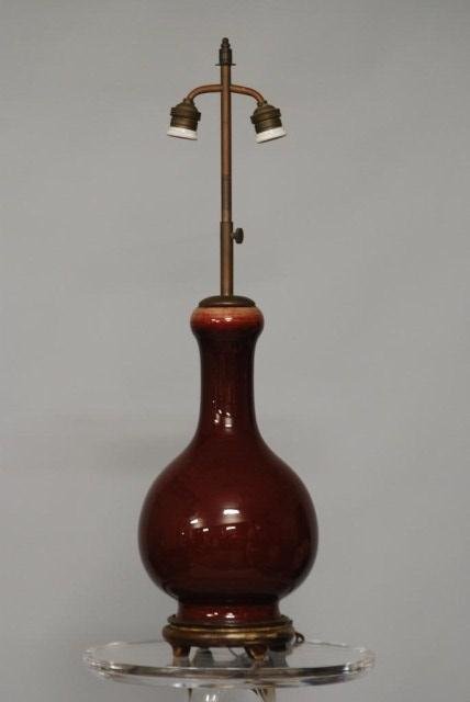 ANTIQUE CHINESE CERAMIC LAMP: Sang de Boeuf glazed Lamp on a wood base, 29 1/2"H X 8"Diameter. In good condition.