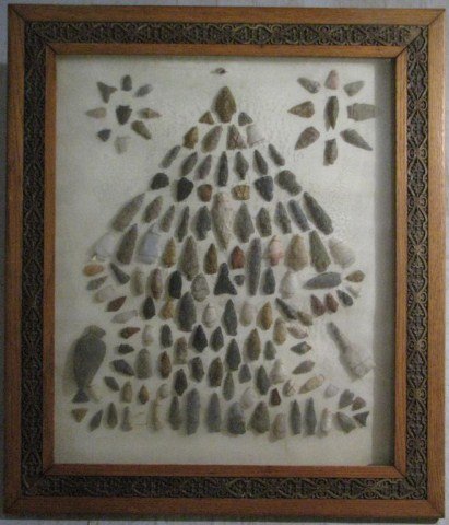 "LARGE PRESENTATION OF N.A. ARROWHEADS AND TOOLS": Ornate oak frame houses 147 chipped stone points. As a mixed lot, their ages probably span from 200 years old through 2000 years old, 26" X 30". Interior hardboard shows buckling and a single inordina