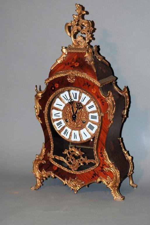 Louis XV Style Mantle Clock: Louis XV Style Mantle Clock. Inlaid king wood with bronze mounts. The dial has porcelain numbers, the movement is made in Germany and is marked "M.H.S.", it has the hanger, pendulum and key. In good c
