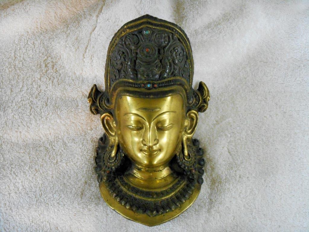 Antique Bronze Indian Diety Mask: Antique bronze Indian deity 8 ½” (h) x 5” (l) face mask with inset carnelian & turquoise stones. Condition: Areas with some form of wear from age & usage.