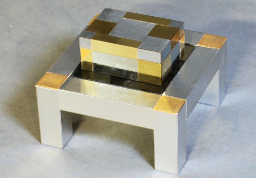 Paul Evans Style Box & Stand: Brass and chrome patchwork clad with removable lid and felt interior. Smoked glass on base. Box measures 3 1/4"H X 7"W X 5"D. Stand measures 10"H X 12"W X 12"D. In good condition.