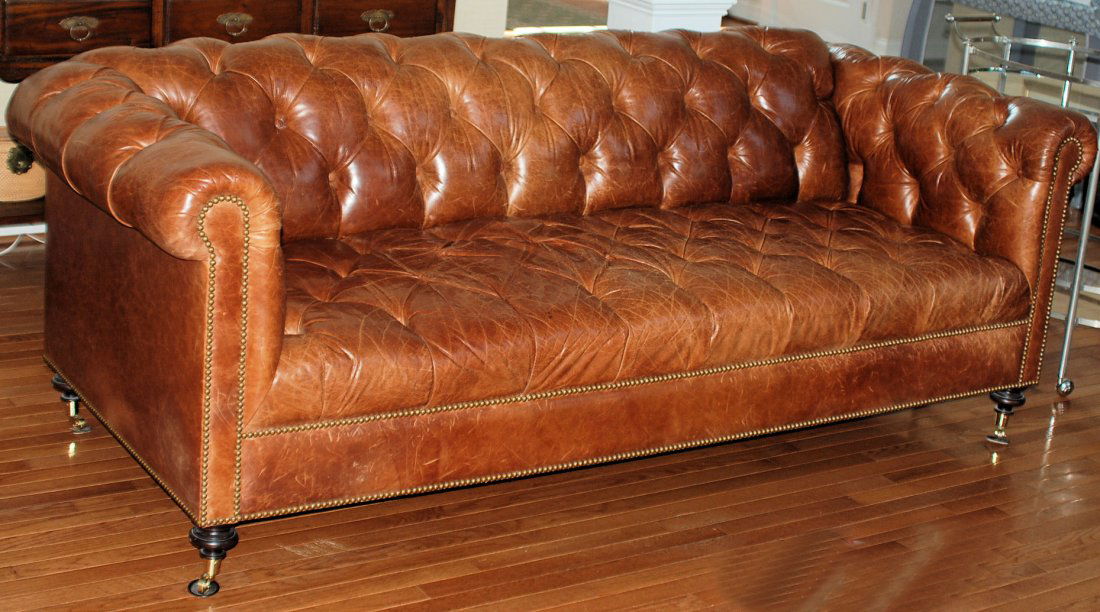 Leather Chesterfield Couch: Tan distressed leather on bun feet with brass cup casters. Several missing buttons, otherwise good condition. 89"W X 33"H X 42"D.