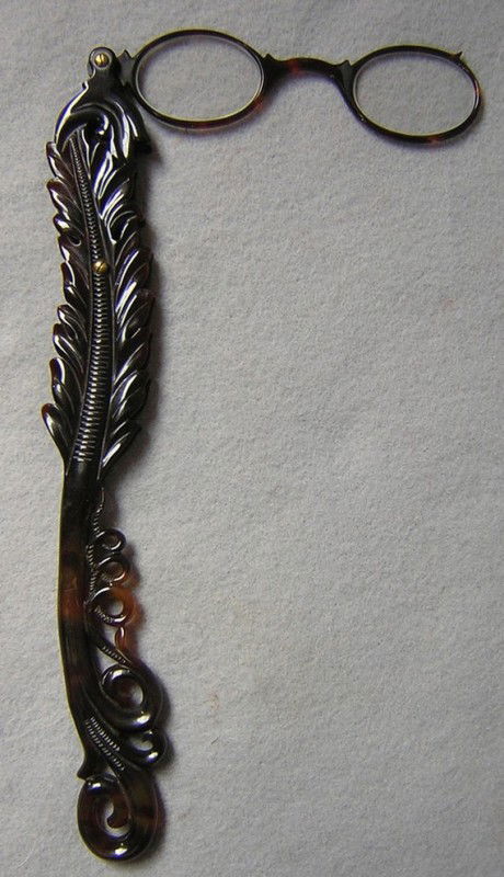 Antique Victorian Carved Tortoise Shell Lorgnette: A lovely antique Victorian pair of lorgnette. The lorgnette feature a tortoise handle and frame with a hand carved leaf or feather motif. There are magnifying lens in the eyeglasses. The lorgnette mea