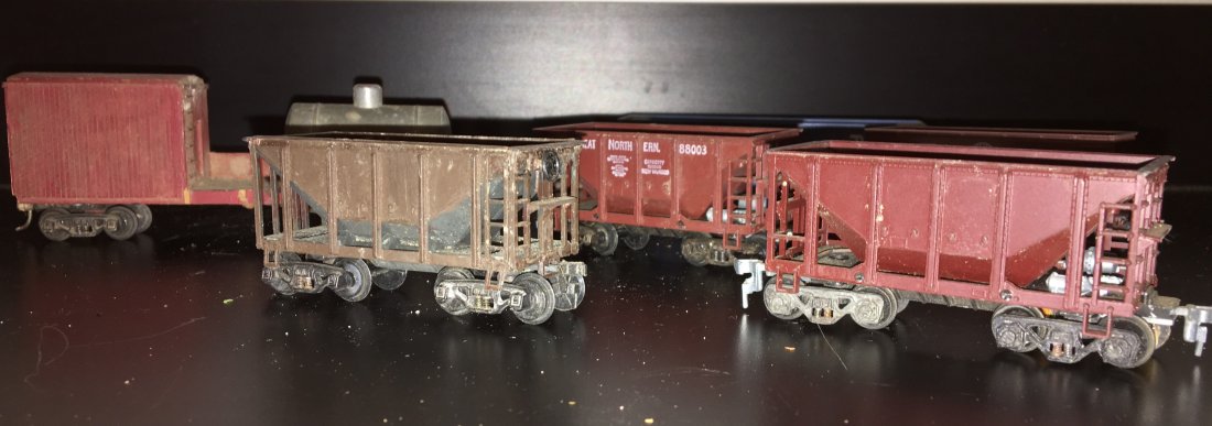 HO Scale Work Cars: An assortment of HO scale work cars. There are 4 ore cars, a wood and metal track cleaning car, and a Boston and Maine operating hopper car with metal bay doors.