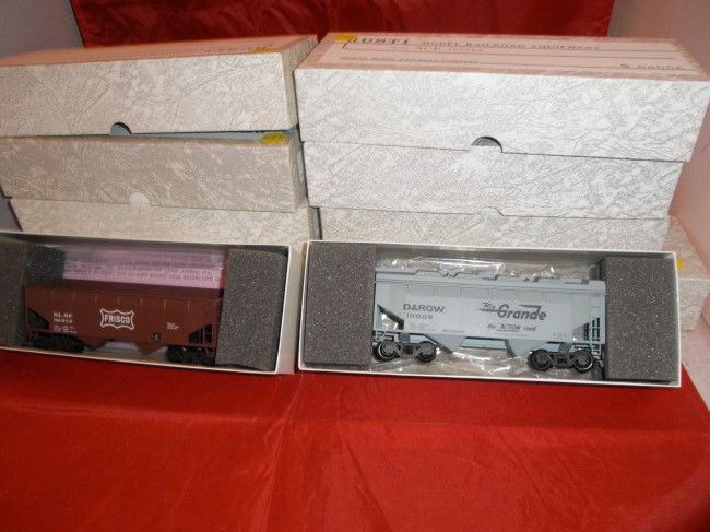 EIGHT (8) RUSTI/DOWNS S GAUGE FREIGHT CARS OB: Eight (8) Rusti/Downs S gauge freight cars in the original boxes. Ace trucks, hopper, gondola, and freight cars. One gondola needs a couple of steps to be reattached.
