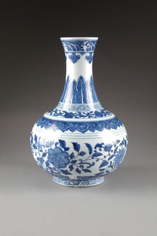 A CHINESE BLUE AND WHITE PORCELAIN VASE,: LATE QING DYNASTY, LATE 19TH/EARLY 20TH CENTURY, of bottle form with large central band of blossoming branches beneath a shoulder of stylized ruyis and a long flaring neck with stiff leaf and ruyi dec