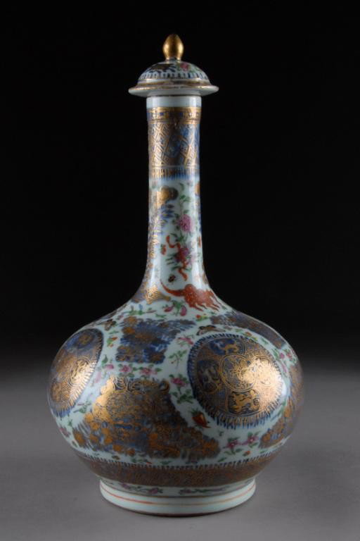 A CHINESE EXPORT PARCEL-GILT FAMILLE ROSE: PORCELAIN BOTTLE VASE WITH STOPPER, LATE 19TH/EARLY 20TH CENTURY, centering circular under glaze blue roundels of qilongs encircling bats and a stylized blossom within scattered flowering stems, butte