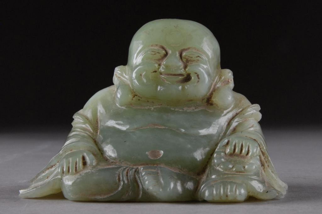 AN ANTIQUE CHINESE BOWENITE JADE: TAO KUANG 1821-1850, carving of Pu-Tai Ho Shang with traditional round and smiling face, pendant ears, abundant belly, with hands resting on knees. Height: 4 1/2"