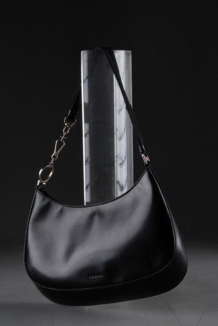 A PRADA BLACK LEATHER HANDBAG, CIRCA 2000: With a single snap top closure, silver-tone hardware, black fabric interior with zippered pocket, and nylon and leather strap. 10 wide, 7 3/8 high