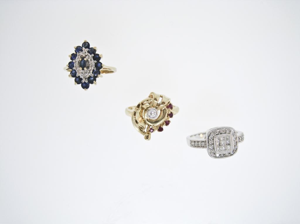THREE 14K RINGS CONTAINING RUBIES, SAPPHIRES AND: DIAMOND, a yellow gold dinner style ring set with 12 round and one marquise shape faceted blue sapphires = 1.00 Ct., and 8 round diamonds = .05 Ct.. Size 6 ¾. (Sizeable). 3.3 grams . 2. A yellow gold