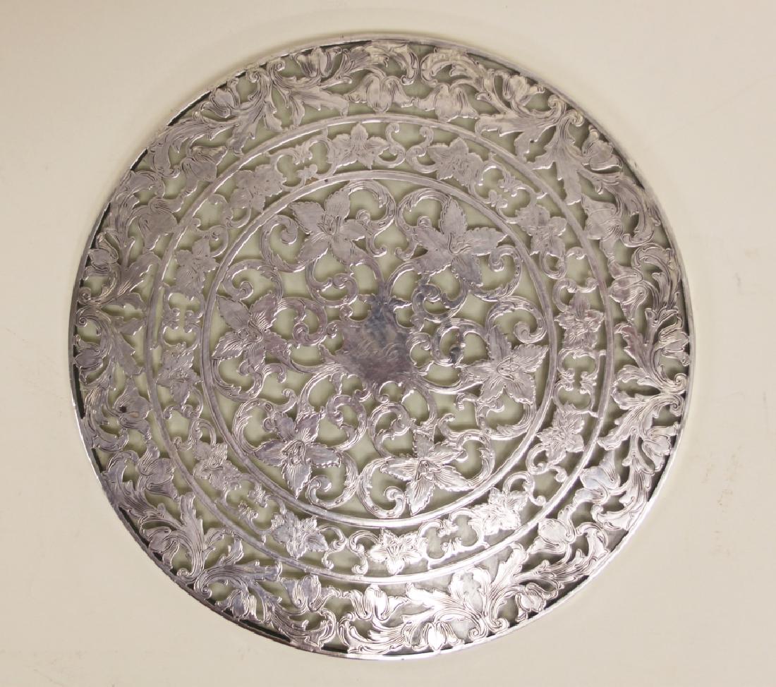 Webster Art Nouveau Sterling Overlay Glass Trivet: Wallace Sterling trivet with floral pattern. Art Nouveau floral pattern with light monogram, "De W". Very good condition (scratch to underside of glass, see photo). Measures 8" dia.
