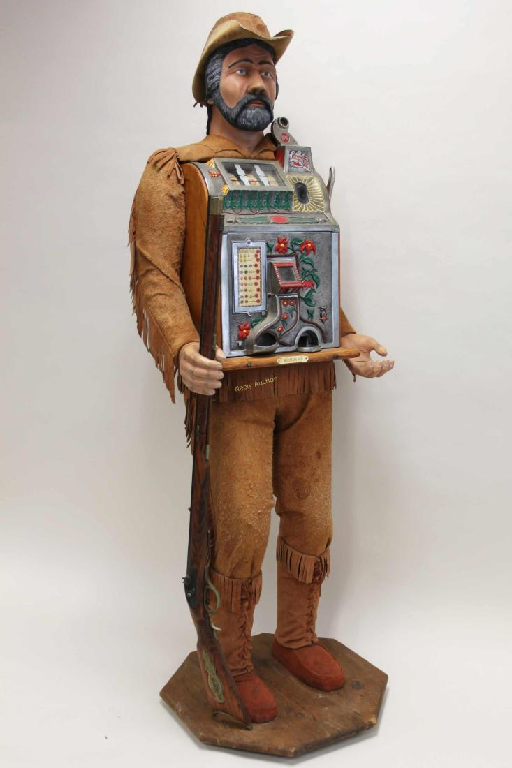 30's Mills Poinsettia 5c Slot Machine Mountain Man: 1930's Mills Poinsettia nickel slot machine mounted in a figural, "Mountain Man" stand. Carved wood and painted figure is dressed in buckskin leather and is holding a flintlock rifle. Excellent condit