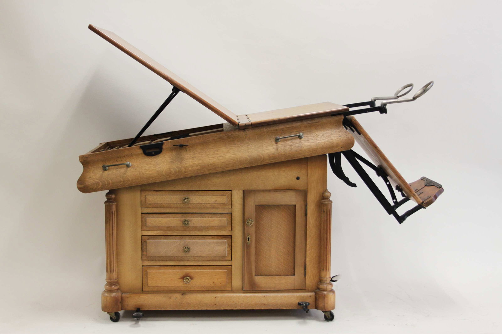 19th Century Medical Exam Table: 19th Century medical doctor's exam table. 1880's golden oak exam table is self contained with stirrups, leg rests(not pictured), drawers and interior shelving. Finished Oak top is adjustable with cast