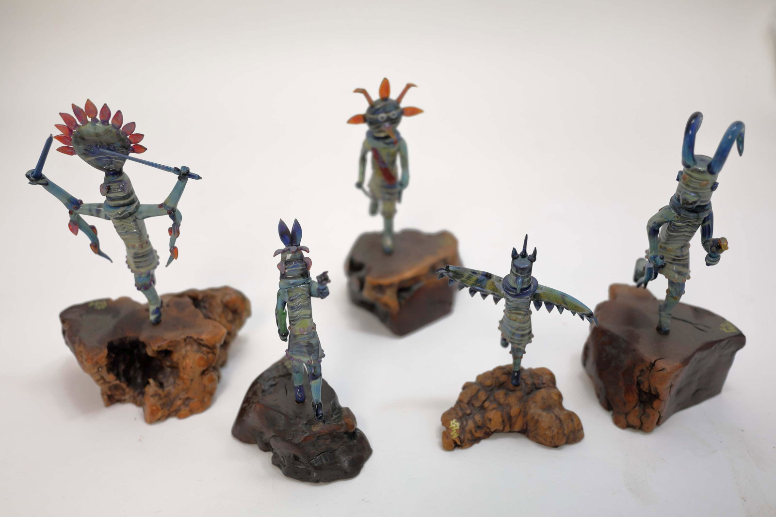 (5) Lewis C. Wilson Art Glass Kachina Immortals: (5) Lewis C. Wilson art glass Hopi Indian Kachina figures representing various immortals in nature. Mounted on burl wood plinths and signed by the artist. .Excellent condition. Measure 5.5" to 9" tall