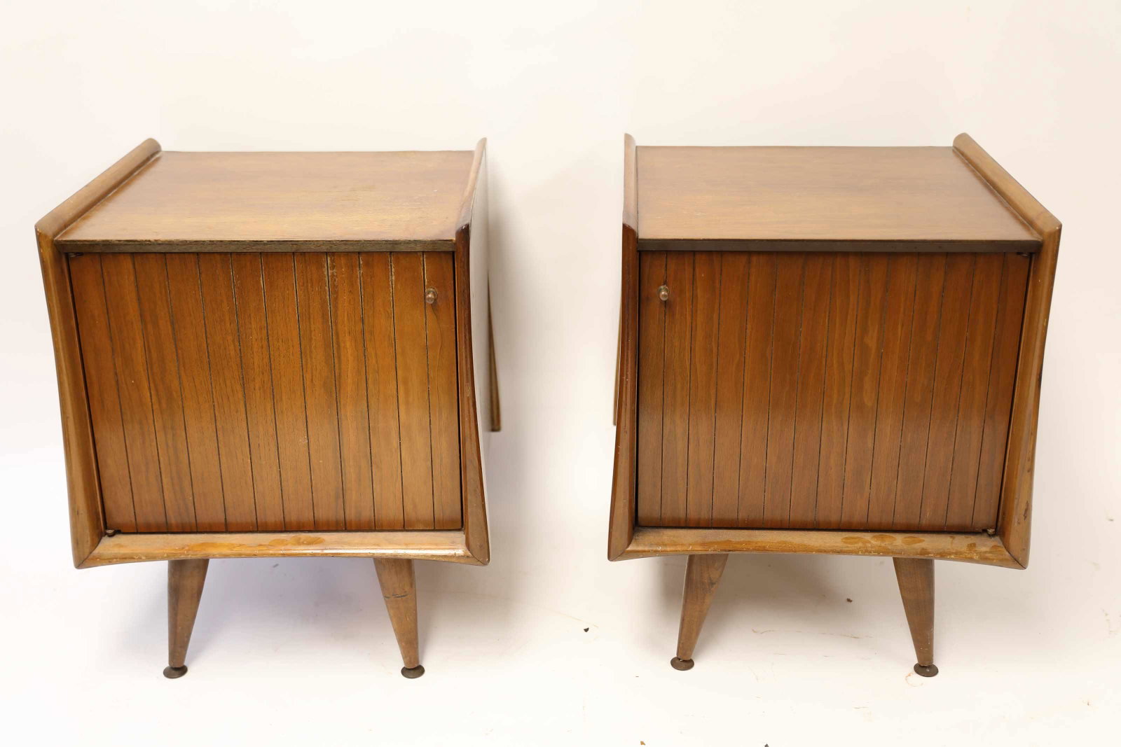 (2) Mid Century Modern Teak Cabinet Nightstands: Pair of two vintage teak nightstands with left and right opening cabinets, containing an adjustable glass shelf. Brass knob pulls and wrapped feet. Excellent / very good used condition, see photos. Me