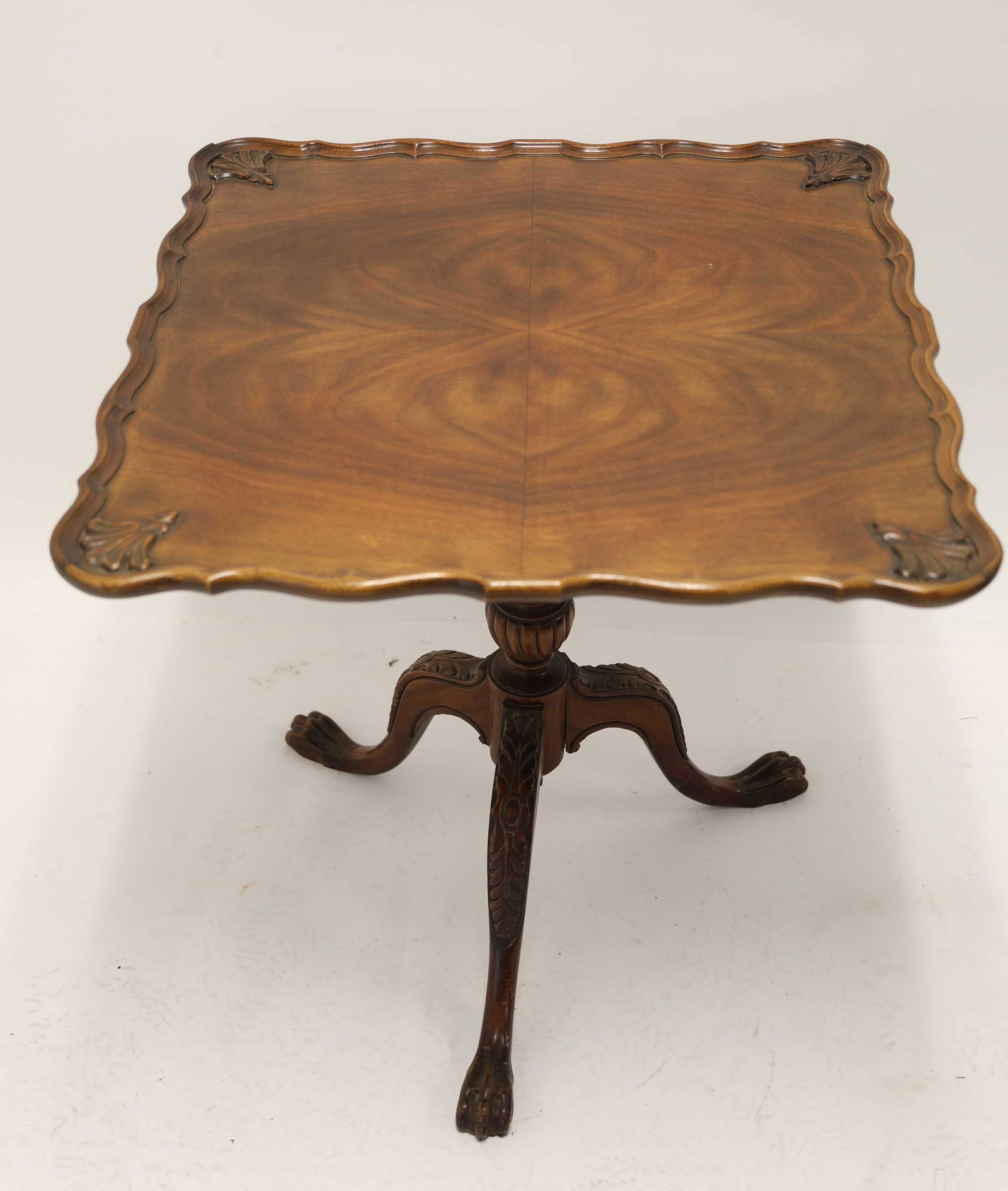 Chippendale Mahogany Tilt Top Fireside Table: 1920's Chippendale mahogany tilt top fireside lamp table. Scalloped top is decorated with carved shells and a pie crust gallery edge, turned and carved base has three claw feet with carved knees. Very