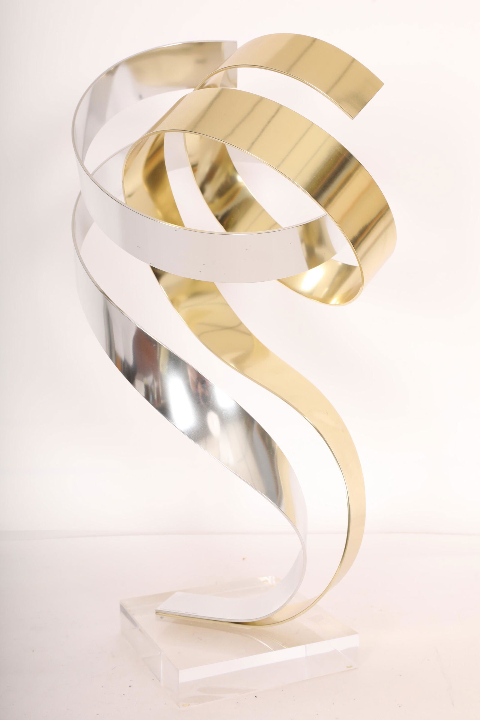 Dan Murphy Abstract Aluminum Ribbon Sculpture: Mid century modern abstract Dan Murphy (American) anodized aluminum ribbon sculpture on Lucite base. Two gold and silver colored ribbons entwine as the ascend. Excellent condition. Measures 20" x 11".
