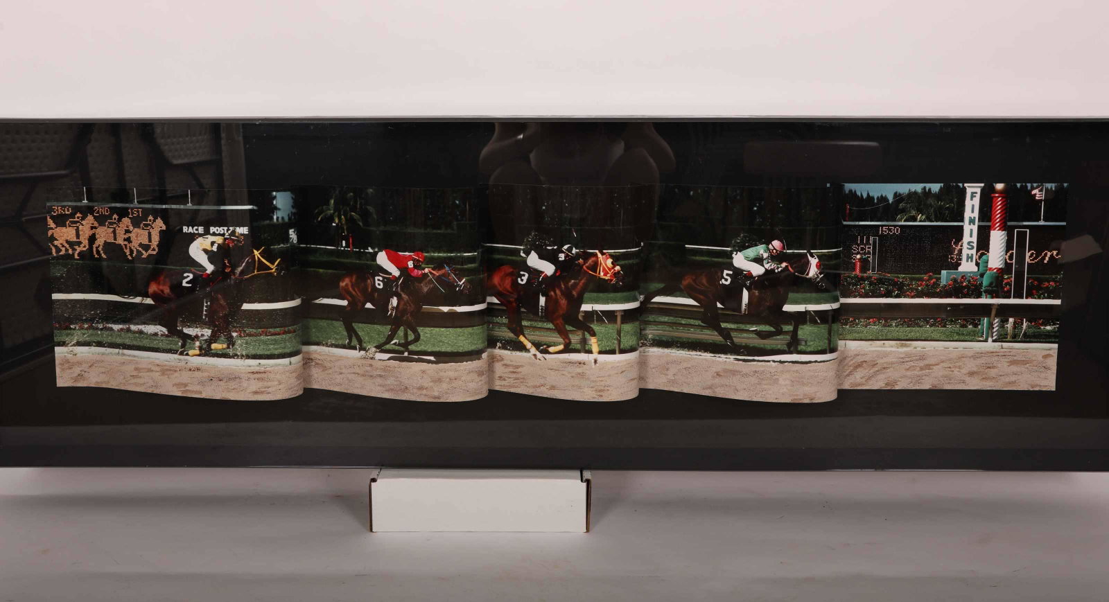Earl Bronsteen Photographic Sculpture "Racetrack": Earl Bronsteen (1926-2014) photographic sculpture "Racetrack" of race horses and their jockeys vying for first place. Composed of large colored images arrayed in a swirling procession. Encased in glas