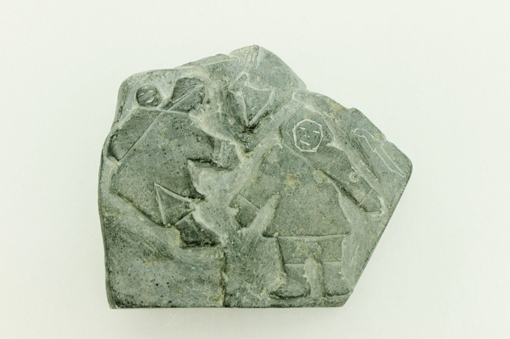 Inuit Eskimo Soapstone Carving: Inuit soapstone carving depicting a family on one side, hunter with seal on the other side and ancestral carvings along the edges. Dimensions: 7 1/2" x 6 1/2" x 1 1/2" Style/Time Period: Early 20th