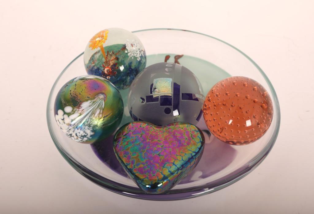 6 Pc Glass Paperweights & James Wilbert Bowl: (6) Pieces lot of glass paperweights and one bowl: (1) inscribed iridescent Roger Vines heart dated 1996, (2) balls with controlled bubbles, (1) Mark S Hembley cobalt blue with dichromatic center date