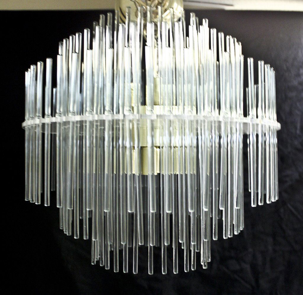 Lightolier Multi-Tiered Crystal Rod Chandelier: Lightolier multi-tiered chandelier with a Lucite armature and crystal rods surrounding a finished brass 3-bulb fixture. Also has brass trim plate. Circa 1970's. Measurements: 17"d x 17"h Period: Mid C