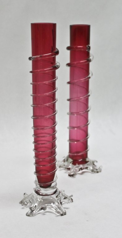 Pair of Victorian Cranberry Art Glass Bud Vases: Pair (2) footed Victorian cranberry art glass bud vases with clear applied rigory. Measurements: 3.25"d x 9.5" Period: Victorian