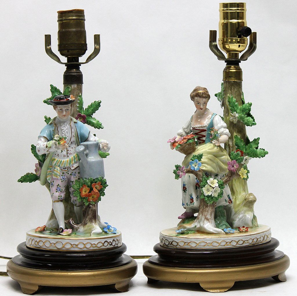 (2) Pair of Dresden Porcelain Figural Lamps: Pair of Dresden porcelain figural lamps; one a young man with a water can, the other a young woman picking flowers. Both lamps are attached to wooden bases. The lady was taken apart in order for us to