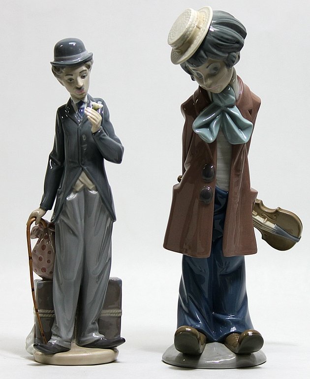 (2) Lladro Porcelain Figurines of Tramps: Two Lladro figurines of tramps. One is titled Charlie the Tramp" and was designed by Juan Huerta and produced from 1984 until 1990. It measures 4" x 3.5" x 11.25". The other is a man holding a fiddle 