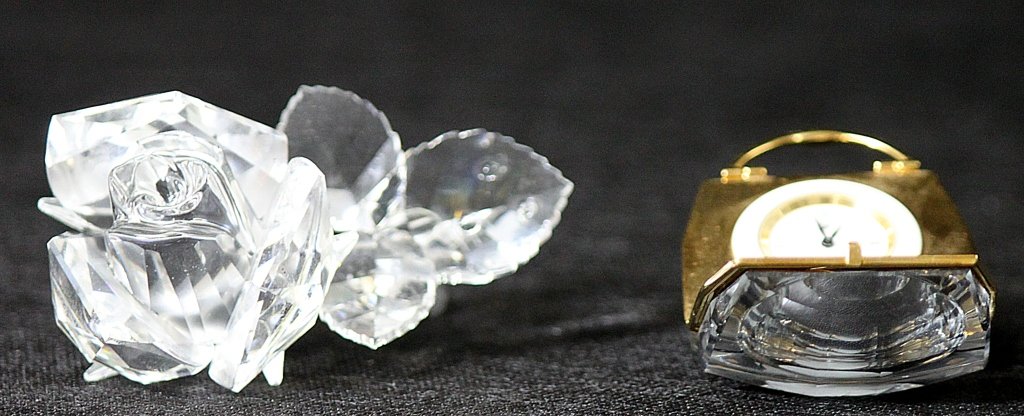 (2) Swarovski Cut Crystal Purse Clock and Rose: Two pieces of Swarovski cut crystal, one is a small bag that opens up to reveal a small clock face, and the other is a rose with dew on the leaves. Both pieces are signed and the purse still has a Mad