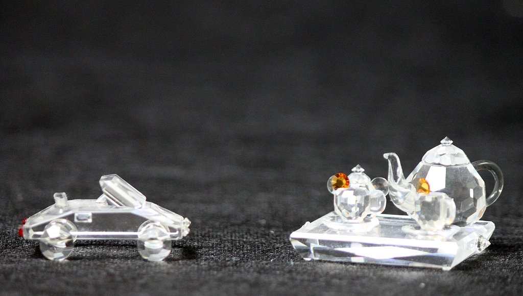 (2) Swarovski Crystal Miniatures, Tea Set & Car: Two Swarovski cut crystal miniatures, one is a car and the other is a tea set with a tea pot, sugar dish, and two tea cups. Neither pieces are marked. The car measures 1.75 x 1" x .75" and the tea set