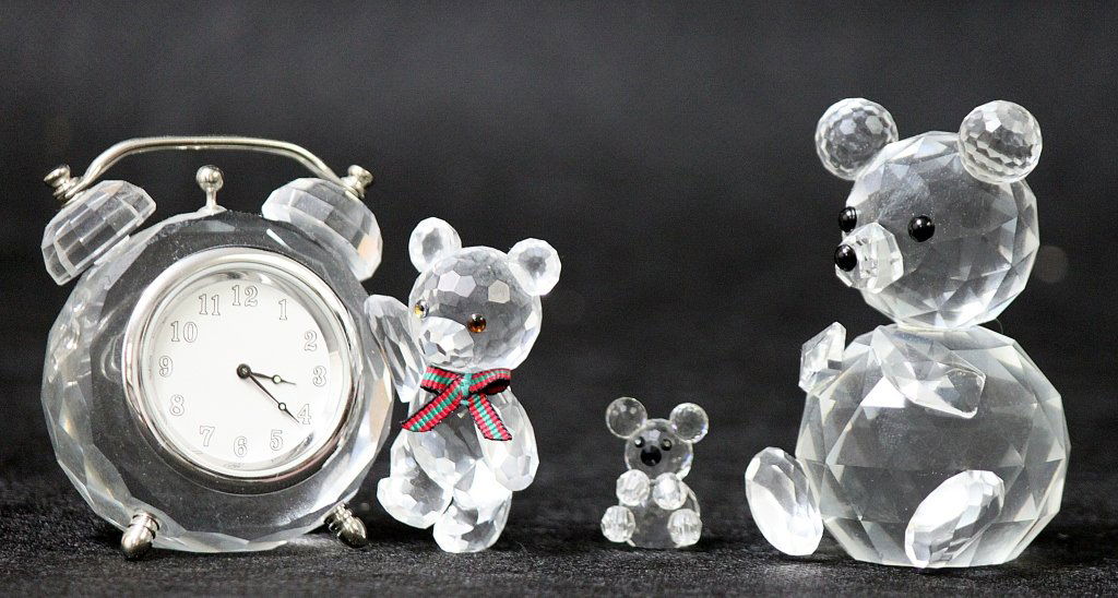 (3) Swarovski Cut Crystal Bears: Lot of three Swarovski cut crystal bears, a large one, a tiny one, and a medium sized one with a decorative clock and red and green bow around his neck. The large one measures 1.75 x 1.75" x 2.75", th