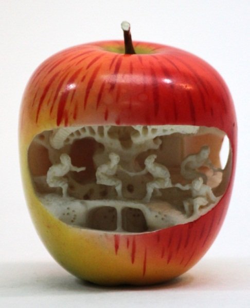 Chinese Ivory Carved Village Scene Inside Apple: Chinese hand carved elephant ivory figural polychromed apple with relief carved village scene. Red and yellow coloring to exterior. Fine detail throughout. Scene depicts villagers doing various activi