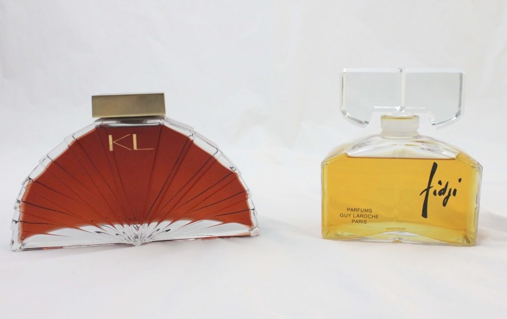 (2) Large Karl Lagerfeld and Guy Laroche Parfums: One over-sized Karl Lagerfeld KL Parfum, and one Guy Laroche over-sized Fidji Parfum in glass. 1.) 2 1/2" x 10 1/2" x 6 1/2" 2.) 3" x 6 1/2" x 7 1/2" Measurements: See Description Period: 20th Century
