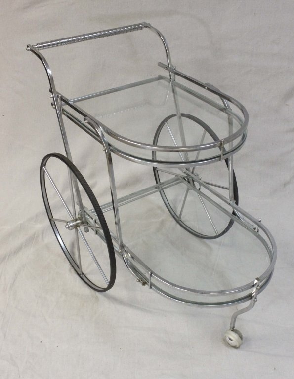 Italian Chrome & Glass Bar Cart: Italian Chromed Metal and Glass Bar Cart, Mid-20th century, Curvilinear frame on two large back wheels and a single front caster supporting two graduated glass shelves with curved ends and galleries. 