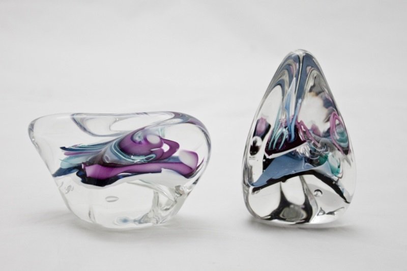 Lot Of 2 Schmidt/Rhea Art Glass Paperweights: Lot of two signed Schmidt / Rhea art glass paperweights. Clear encased glass with abstract multi-color details. Both signed on bottom. Triangle Measures 2.5" x 4.5" Oblong Measures 4" x 2" x 3" Measur