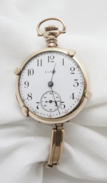1913 Womens 14K Gold Plate Elgin Watch w/ Band: 1913 Womens 14K Gold Plate Elgin watch with clamp on gold filled watch band. On inside of open face pocket watch stamped SEVEN JEWELS 17734077 ELGIN USA and on lid EXCELSIOR W. CO GUARANTEED 20 YEARS.