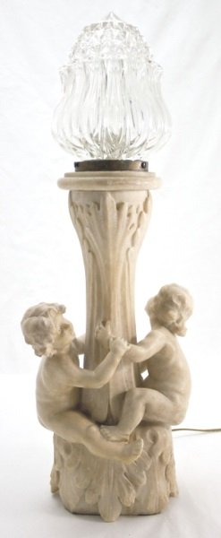 Alabaster Lamp w/ Puttis Around Tree Trunk: Figural Putti carved alabaster lamp. Carved white alabaster tree trunk form base has 2 full standing putti around center torchiere. Total height including glass shade is 26" tall. Dimensions: 8" x 6"