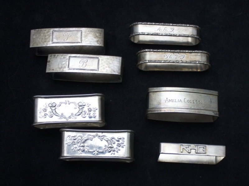 8 Assorted Sterling Silver Napkin Rings: 8 Sterling silver napkin rings, lot includes: 2 oval napkin rings engraved "A.E.G. & H.J.G" , marked Sterling 765- measures 2.5" x .73". 2 Square silver napkin rings engraved "B" & "J", marked Sterlin