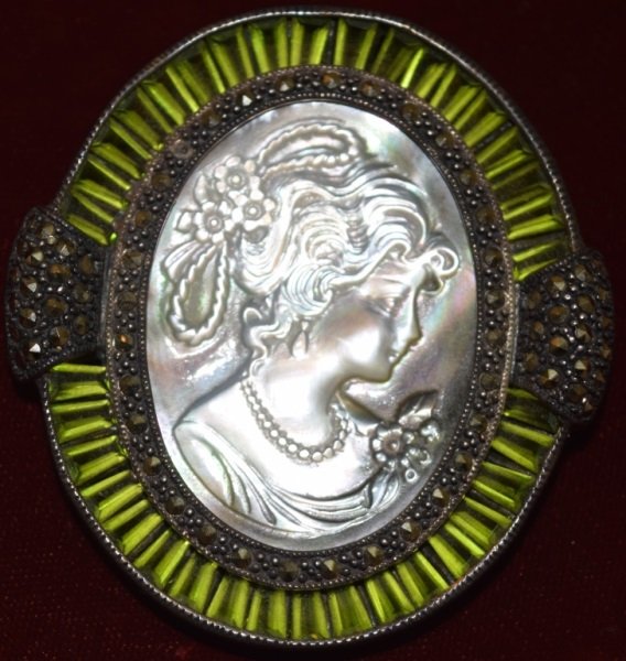 Sterling Silver Cameo Mother Of Pearl Brooch: Sterling silver brooch or pendant mother of pearl shell cameo with marcasite and baguette cut green stones surrounding pendant brooch. Marked 925 2.5" x 2" x .5"