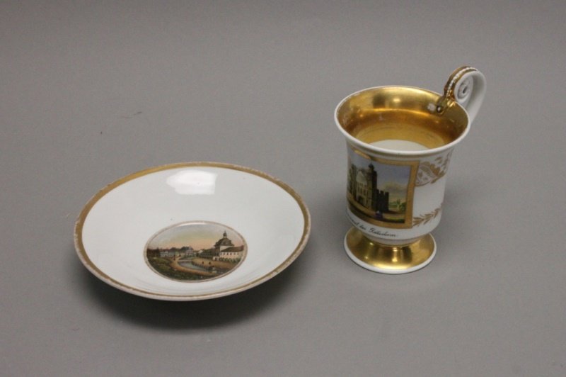 19th C KPM Cup Pfaueninsel Potsdam, Dresden Saucer: 19th century KPM hand painted porcelain cabinet cup and Dresden saucer with architectural imagery. KPM cup is decorated with an image of the Pfaueninsil Palace in West Berlin with inscription beneath:
