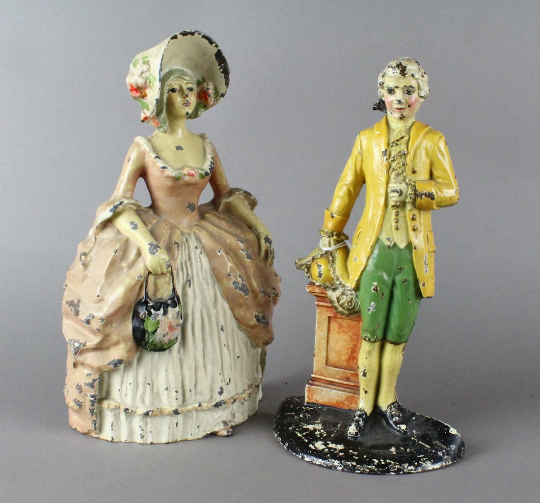 Cast Iron Colonial Man & Woman Doorstops: Cast Iron Colonial Man & Woman Doorstops. Woman wearing large bonnet with puffed out hooped skirt. Fine condition 10 - 1/4 inches tall. Colonial Lawyer 9 3/4 inches tall by 5 1/2 inches wide.