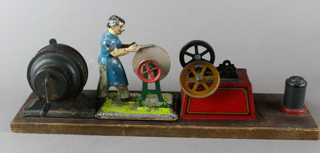 German Tin Grinder Man & Hess Dynamo Steam Toy: German Tin Grinder Man & Hess Dynamo Steam Toy. Crank The flywheel in the German Hess Dynamo to power steam toys by pulley drive. Dyanamo is working. Grinder toy Bing or early Arnold.
