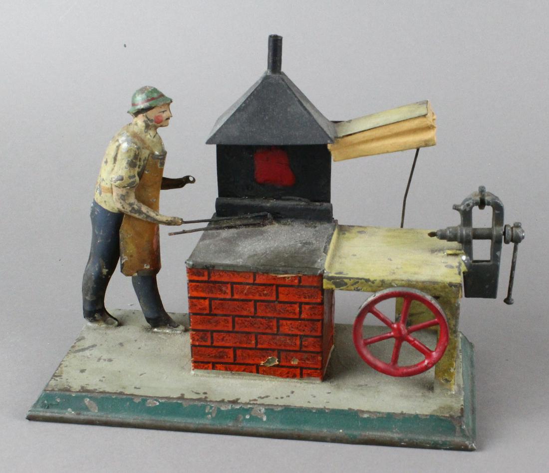 German Tin Steam Toy Blacksmith at Forge: German Tin Steam Toy Blacksmith at Forge. Larger forge with work stand blacksmith and fire.