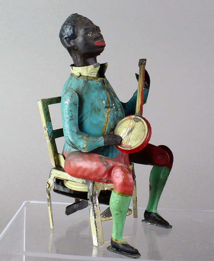 1900s Gunthermann German Tin Banjo Player: Gunthermann German Tin toy Banjo Player. Extremely fine hand painted original c.1910 German wind up toy. African American Banjo player strums and moves legs and head while a plinking sound occurs simu