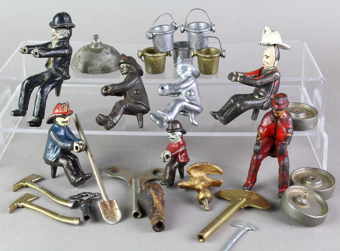 Hubley, & More Parts- Drivers, Firemen: Cast Iron 5 Firemen, Derby Cap Driver, Arcade Driver, Fire Brigade buckets, Eagle, Key winders, Shovel, and Fire Axe along with train wheels.