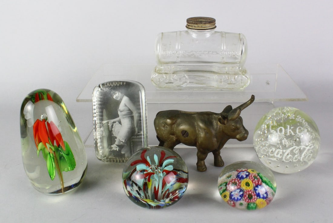 Bull & Glass Tanker Still Banks & Blown Glass Paperweights: Mixed lot of cast iron Bull Bank, Tanker System Saves bank, and 5 glass paper weights of Millefiori flowers, Coca-Cola, Risque Nude paperweight and floral blown glass designs. Tanker is 4 inches long.